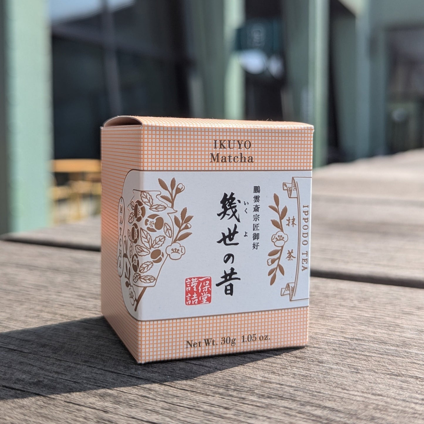 IKUYO Matcha packaging on a wooden surface with a blurred background